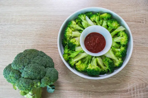 Blanched broccoli, vinegared red chili pepper paste and raw broccoli on wooden background.