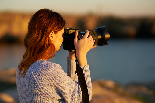 woman with professional camera at sunset by the sea. High quality photo