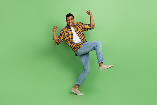 Full body photo of overjoyed nice person raise fists shout yeah triumph isolated on green color background.