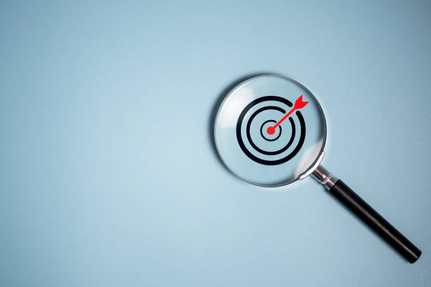 istock Target board inside vintage magnifying glass  for focus business objective on blue background and copy space. 2120042545