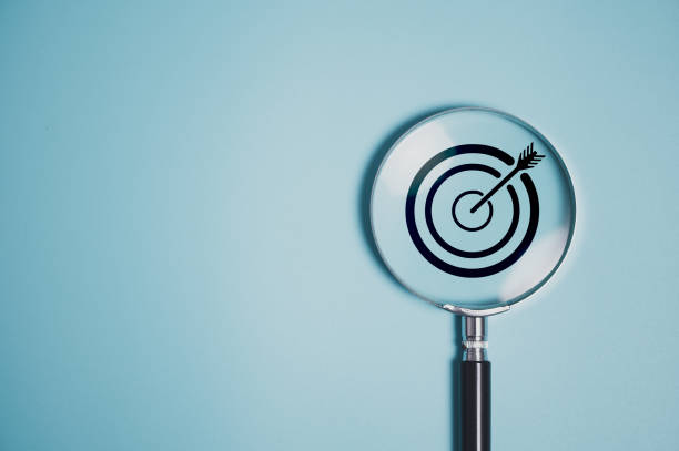 istock Target board inside vintage magnifying glass  for focus business objective on blue background and copy space. 2120042600