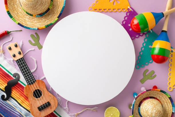 istock Cinco de Mayo setup. Top view capturing iconic elements: sombreros, vihuela, maracas, mustaches, a striped serape, flags, chili peppers, confetti on a light purple background, circular space for copy 2120048652
