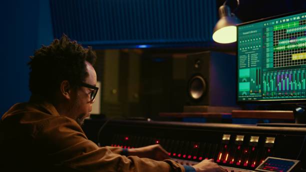 istock African american producer working at mixing panel in recording studio 2120074864