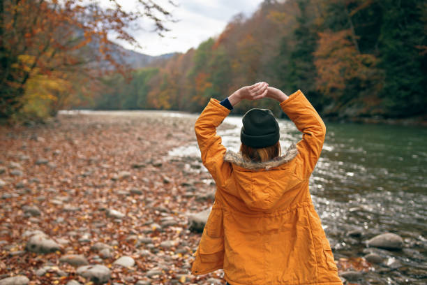 woman throws up her hands in nature Autumn forest river fallen leaves. High quality photo
