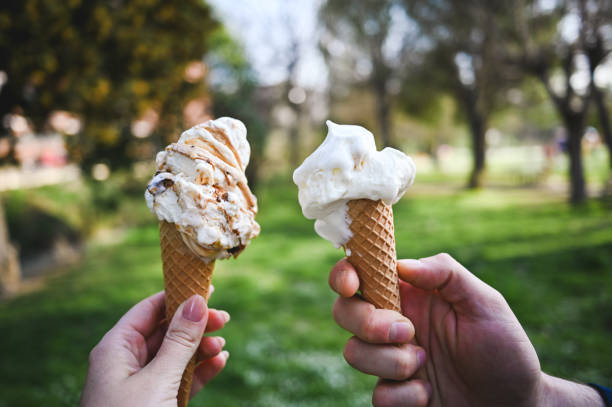Friends eating ice-cream cone in parkland.