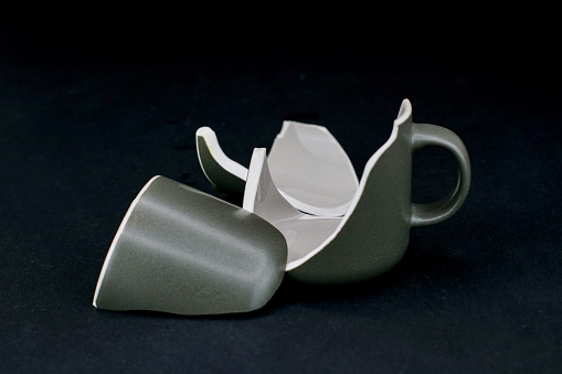 A broken ceramic coffee or tea cup. Black background