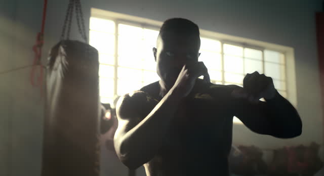 Boxing, fitness and black man for sport, exercise and workout with punching bag in gym. Male person, boxer and athlete in gymnasium for wellness, training and competition with technique or punch