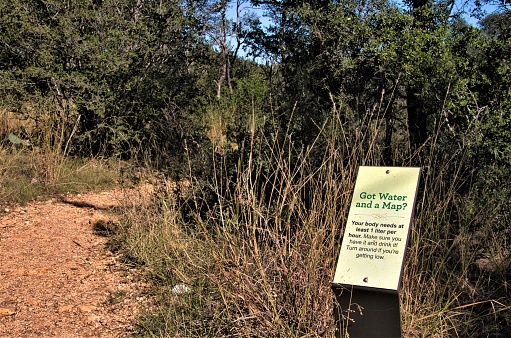 On a hot Summer day at Colorado Bend State Park in Texas, a sign warns hikers to be sure to bring water and a map.