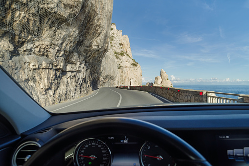 Seen from inside the car the stunning high altitude cliffside road along the coastline of Liguria, Italy