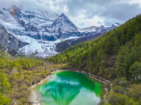 Beautiful scene of mountain and lake at SiChuan, China.drone aerial view of Yading nature reserve in china. snowy Chenrezig picturesquely surrounded by evergreen trees and lake