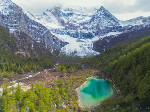 drone aerial view of yading nature reserve in china. snowy chenrezig picturesquely surrounded by evergreen trees and lake - silk pearl imagens e fotografias de stock