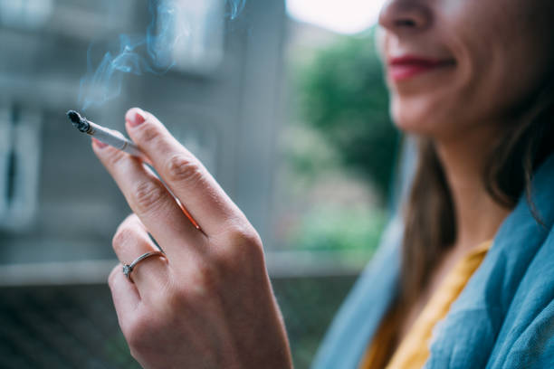 young woman smoking a cigarette outdoors. - smoking women smoke smoking issues foto e immagini stock