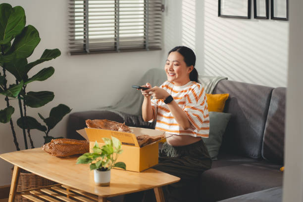 istock Asian woman using smartphone taking a photo while unpacking, enjoying online shopping. 2120183696