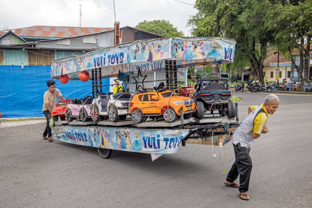 Sabang, Pulau Weh, Indonesia - January 13th 2024:  Men pulling part of a merry-go-round with toy cars through the street