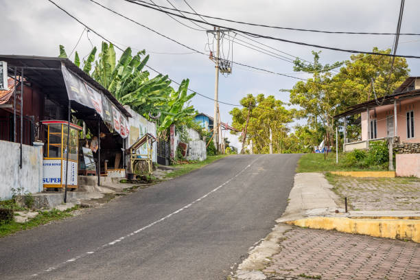 Sabang, Pulau Weh, Indonesia - January 14th 2024:  Road in rural surroundings with small shops and electric wires outside a typical Indonesian town