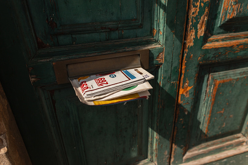 Vintage Newspaper sticking out of the mail in the door. Vintage green antique door with mail and newsletter