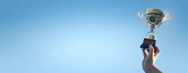 istock Winner holding up a first place sporting trophy cup background 2120250225