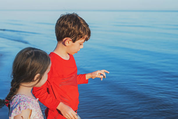 Brother and sister take a close look at a small sea snail.