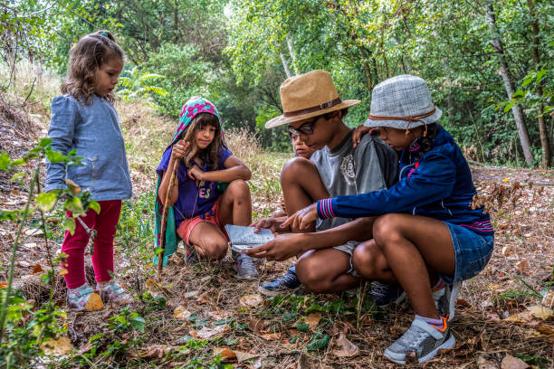 istock Young explorers on a forest adventure, learning and fun merge in children's play. Diverse group consults a map, embodying the spirit of discovery. Childhood and diversity concept. 2120261807