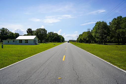 Two lane road in rural small town blue sky background