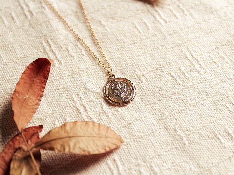 Composition with a necklace and autumn leaves on a cotton linen fabric background.