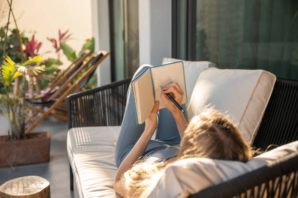 istock Young woman journaling surrounded by potted plants on her balcony 2120300890