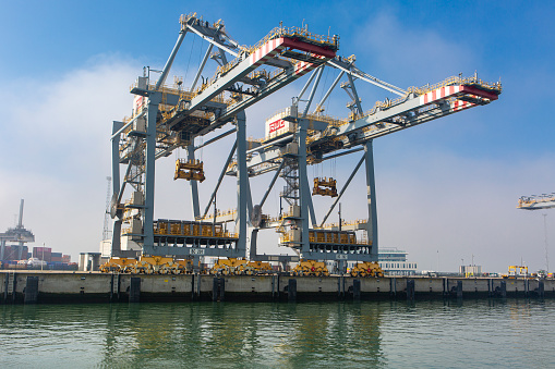 Rotterdam, The Netherlands: March 06, 2024: Large gantry cranes and container ship - port of Rotterdam - Maasvlakte. The Maasvlakte is a massive westward extension of the Europoort port and industrial facility within the Port of Rotterdam.