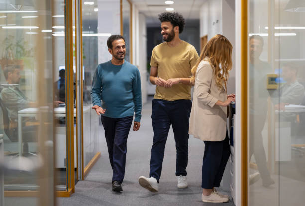 istock Coworkers chatting and walking in office corridor 2120325224