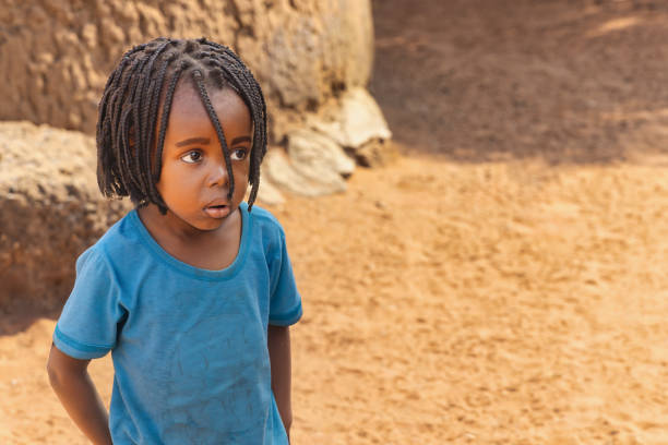 portrait of an african kid girl with braids playing in the yard , african village life