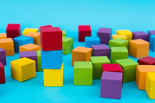 Heap of wooden toy blocks on blue background.