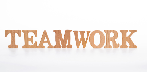 Wooden word teamwork on white background.