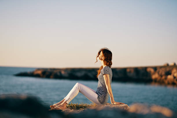 woman by the sea sits on a large stone side view. High quality photo