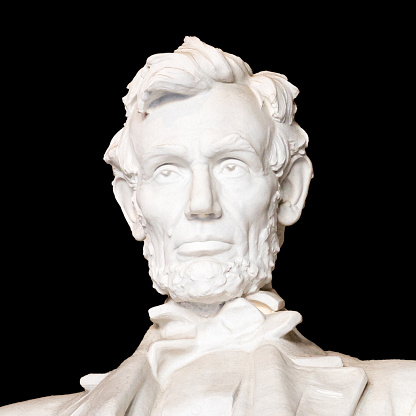 Detail of the head and shoulders of US President Abraham Lincoln, located within the Lincoln Memorial in Washington DC, against a black background.