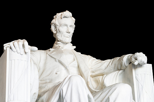 A low angle view of the statue of US President Abraham Lincoln, located in the Lincoln Memorial in Washington DC, against a black background.
