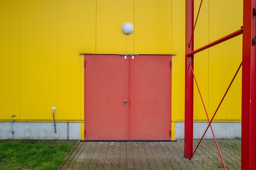 large red metal door in yellow house wall