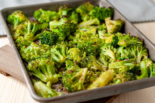 Oven roasted broccoli florets on an aluminum sheet pan with garlic and red pepper flakes