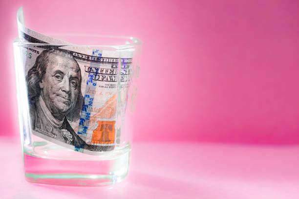 istock 100 dollar bill in whiskey glass 2120399229
