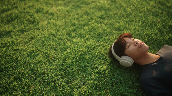 Asian teenager boy napping on the grass.
