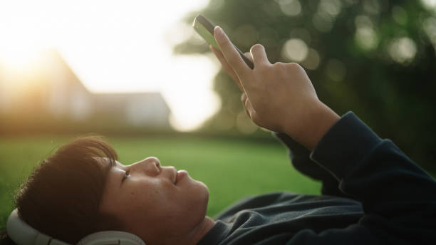 teenager boy using smartphone while relaxing at green environment. - peace on earth audio zdjęcia i obrazy z banku zdjęć