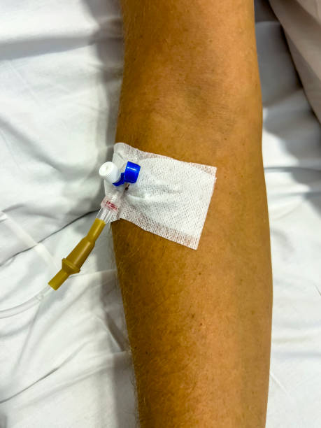 istock Close-up view of forearm with IV drip, vertical. 2120400819