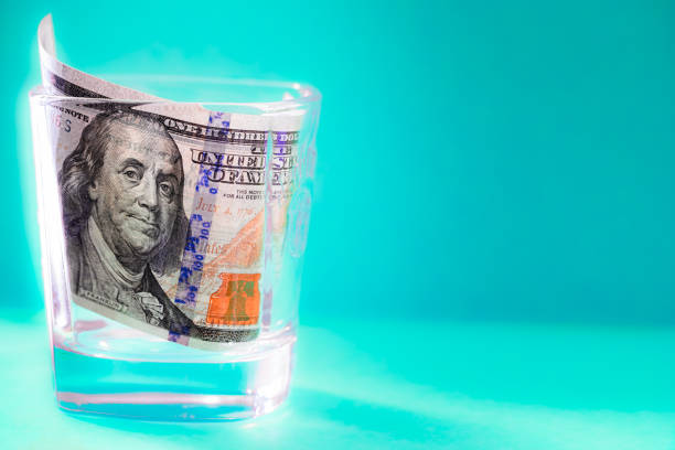 istock 100 dollar bill in whiskey glass 2120401340