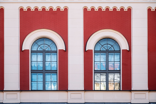 Two arched windows with gray frames against a red brick wall with columns. From the series Window of the World.