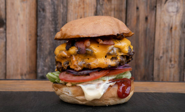 istock Delicious multilayer burger with a rustic wooden background 2120459448