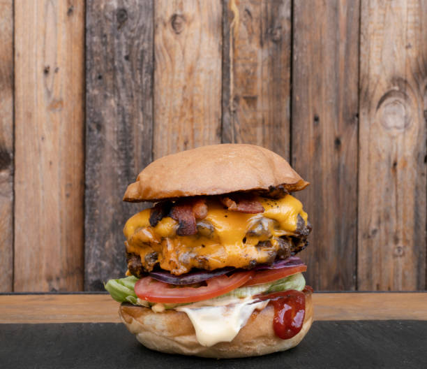 istock Delicious multilayer burger with a rustic wooden background 2120459539