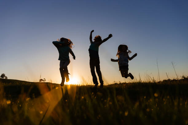 Silhouette of three siblings at sunset in a field