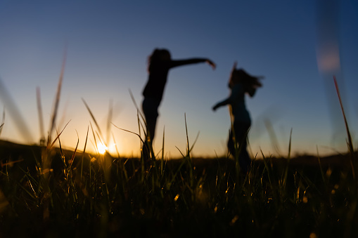 Silohouette of a mother and daughter dancing in a field