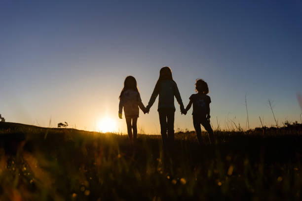 istock Silhouette of three siblings at sunset in a field 2120477160