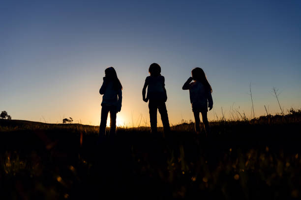 Silhouette of three siblings at sunset in a field