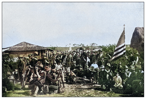 Antique black and white photograph of people from islands in the Caribbean and in the Pacific Ocean; Cuba, Hawaii, Philippines and others: American soldiers resting in a Cuban village