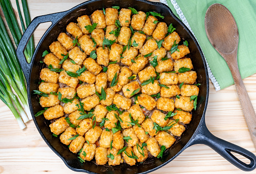 American classic hot dish casserole comfort food with tater tots, beef, and mixed vegetables baked in a cast iron skillet.